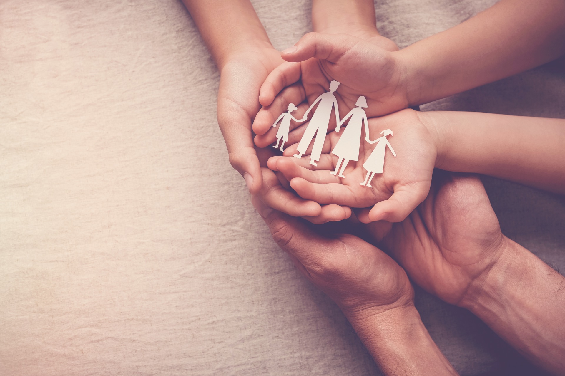 3 generations of hands holding paper cutout of family