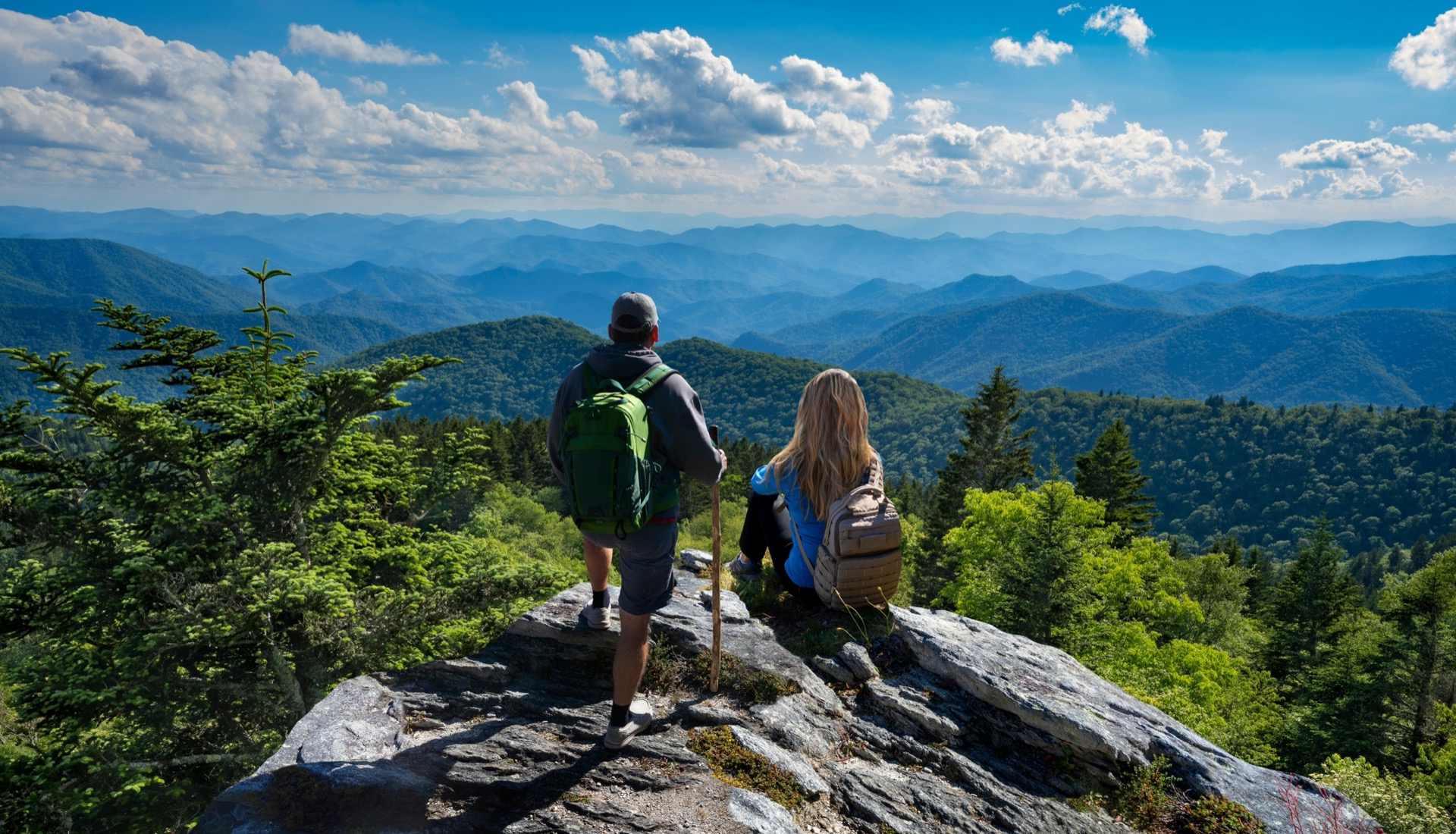 Two hikers looking out over green hills