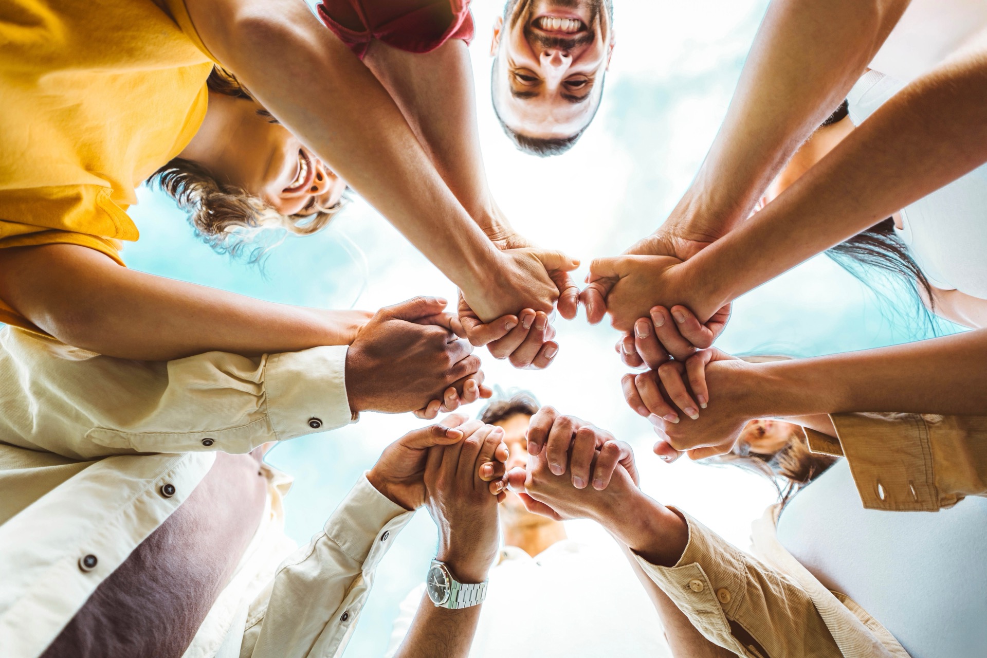 Group of people holding hands, viewed from below